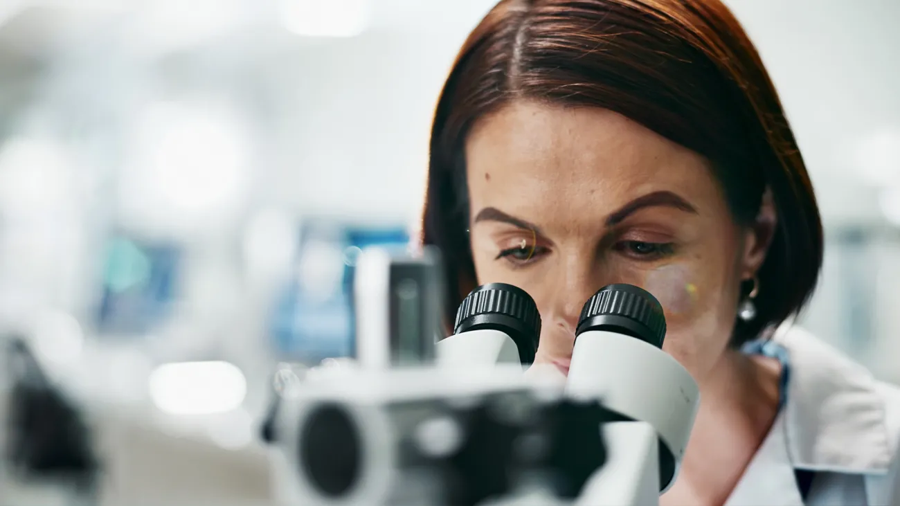 forensic scientist looking into microscope